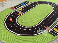 a crocheted rug with cars and trucks on the road is shown in green