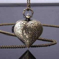 Step back in time with this antique reproduction pocket watch. The front door is an elaborate design of open work scrolls. A small clasp on the side is the closure. Inside, a glittery heart is the background for the delicate hands. Quartz movement and includes a 28-inch chain with lobster claw clasp to be worn as a necklace. The clock case measures approximately 2 inches long x 1.5 inches wide. Material: Bronzed alloy Movement: Quartz/Battery Operated Size: Chain length 28 inches Operating Instr Antique Gold Quartz Pocket Watch As Gift, Antique Gold Metal Pocket Watch With Antique Finish, Gold Engraved Steampunk Pocket Watch, Vintage Metal Pocket Watch With Antique Finish, Vintage Bronze Metal Pocket Watch, Antique Bronze Metal Pocket Watch, Vintage Metal Pocket Watch As Gift, Elegant Locket Pocket Watch For Gift, Steampunk Engraved Pocket Watch As Gift