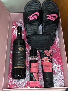 an open pink box containing two bottles of wine and other personal care items in it