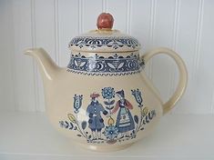 a blue and white tea pot with an ornate design on the front, sitting on a shelf