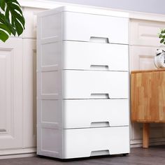 a white chest of drawers next to a potted plant