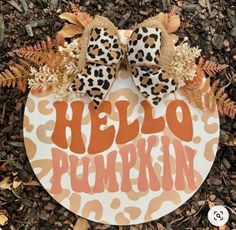 a hello pumpkin door hanger with an orange and black leopard print bow on it