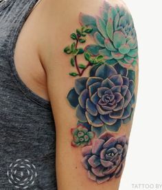 a woman's arm with succulents and leaves tattooed on the shoulder