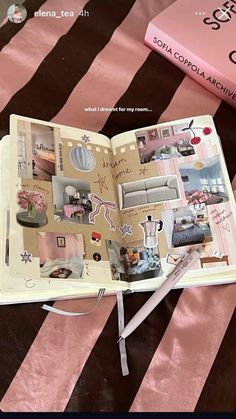 an open book sitting on top of a bed next to a pink and black striped blanket