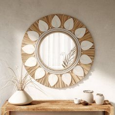 a mirror on the wall above a wooden table with two vases and a potted plant