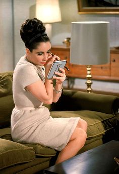 a woman sitting on top of a couch holding a cell phone