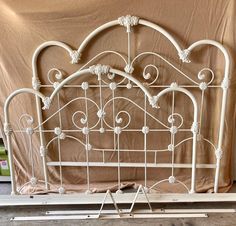 a white iron bed frame sitting on top of a wooden floor next to a wall