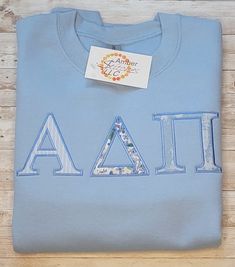 a light blue shirt with the letters aa on it