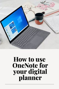 an open laptop computer sitting on top of a desk next to a cup and notebook