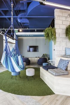 a living room filled with furniture and hanging hammock chairs on top of green rugs