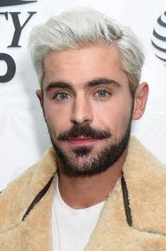 a man with white hair and beard wearing a tan jacket