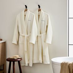 two robes hanging on the wall next to a bath tub