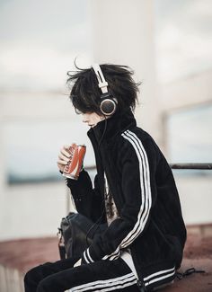 a person sitting on the ground with headphones on and holding a can in their hand