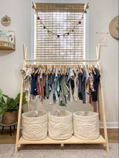 a rack with clothes hanging on it and two buckets in front of the rack