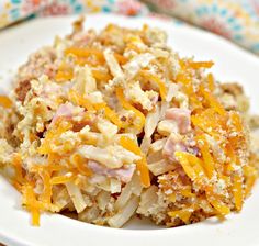 a white plate topped with potato salad covered in grated cheese and meat toppings