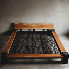 a bed frame made out of wood and metal with circles on the bottom, sitting against a gray wall