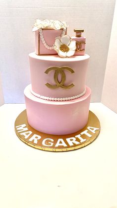 a pink and gold cake with chandelier decorations on the top is displayed in front of a white wall