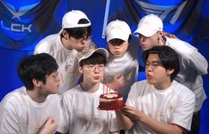 a group of young men standing next to each other in front of a birthday cake