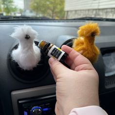 a person is holding an electronic device in their hand and two stuffed animals are on the dashboard