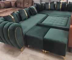 a large green couch with gold trimmings in a room filled with brown furniture