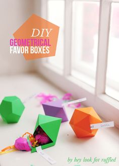 several colorful paper boxes sitting on a window sill with the words diy geometric favors