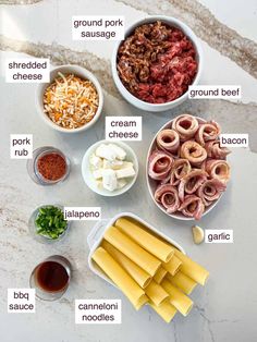 the ingredients for an italian pasta dish laid out on a marble counter top, including meats, cheese and sauces