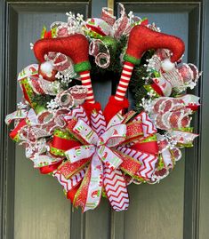 a christmas wreath with red and green decorations hanging on the front door, decorated with candy canes