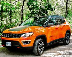 an orange jeep is parked in the woods