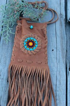 a brown leather purse with fringes and beads on it sitting on a wooden surface