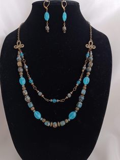 I made this gorgeous double-strand necklace and matching earrings with Impression Jasper stones, Aqua Blue Chalcedony oval beads, and Czech glass. The set is accented with antique bronze finish metal beads made of pewter alloy and zinc alloy. All metal is lead/cadmium/nickel free. The necklace consists of two strands of beaded and wire-wrapped beads attached to 2 pretty pewter alloy links with an antique bronze finish. The chain is made of steel and the closure is a hook-type clasp.  The necklace is 25 inches long. The earrings have leverback ear wires and their drop length is 1 1/2 inches. Beads featured in this set: - Impression Jasper, round and rectangle stones in 10mm, 8mm, 6mm - Chalcedony, 14mm faceted oval beads - Czech glass, 6mm aqua blue round beads These are handmade pieces. Al Vintage Multi-strand Gemstone Beads Jewelry, Vintage Multi-strand Jewelry With Natural Stones, Elegant Multi-strand Turquoise Jewelry, Elegant Turquoise Multi-strand Jewelry, Elegant Blue Beaded Nickel-free Necklace, Multi-strand Czech Glass Gemstone Beads Jewelry, Turquoise Multi-strand Jewelry For Jewelry Making, Multi-strand Czech Glass Jewelry With Gemstone Beads, Elegant Multi-strand Czech Glass Necklaces