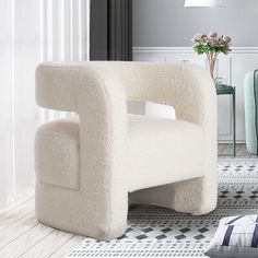 a white chair sitting on top of a rug next to a table and chairs in a living room