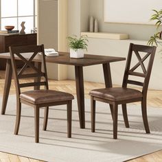 a dining room table with two chairs and a potted plant on the floor next to it