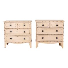 a pair of white dressers with black knobs on each drawer and two drawers