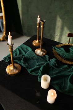 three candles are sitting on a table next to a green cloth and some other items