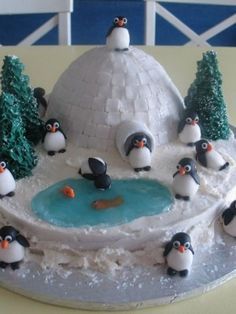 there is a cake with penguins on it and trees in the snow around them,