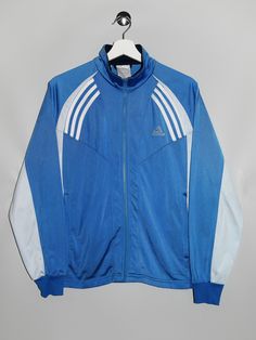 "Vintage Adidas Track Jacket  - Size tag: Please always check measurements before buying. Tag is faded, Fits Women's L - Measurements (laying flat): Pit to Pit: 21\" Length: 25\" Pit to Cuff: 20\" -Wear: /Please see images for details/ Overall in good vintage condition. Zip pull is missing -Flaws: / serious wear, tears, holes, marks or stains/ Please see images for details. None. - Fabric: 100% Polyester  *All of our items are preloved pieces so some signs of natural wear and age are to be expected. Please look through the photos carefully to check if the condition is to your satisfaction. *All efforts are made to show any defects however small imperfections may be missed. *We try to describe the sizes as accurately as possible, but please keep in mind that sizes nowadays can differ to siz Luxury Blue Winter Track Jacket, Cheap Blue Track Jacket For Sports, Cheap Blue Adidas Activewear, Blue Retro Outerwear For Sports Events, Blue College Track Jacket With Pockets, Blue Track Jacket With Pockets For College, Blue Hooded Outerwear With Three Stripes, Vintage Track Jacket For Sports Season, Vintage Track Jacket For Sports