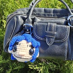 a handbag with a crocheted face hanging from it's side on the grass