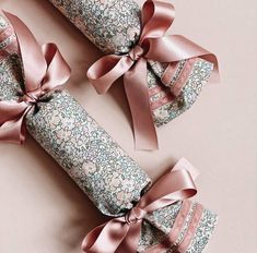 three rolled up rolls with pink bows on the top and bottom one wrapped in brown paper