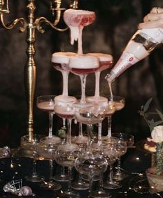 champagne being poured into wine glasses in front of a candelabra with candles