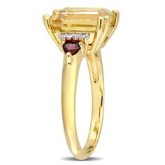 Bring a touch of opulence and timeless charm to your look with Citrine, Garnet and Diamond Accent 3-Stone Cocktail Ring. Crafted in radiant yellow gold plated sterling silver, it features an octagon-cut, multi-prong-set citrine gemstone (10 x 8mm) at the center flanked by two trilliant-cut, prong-set garnet gemstones (3 x 3mm) it features eight round-cut, prong-set diamond accents (G-H, I2-I3). Enhanced with a high polish finish, this gorgeous ring is sure to draw attention. Formal Three Stone Yellow Jewelry, Formal Yellow Three Stone Jewelry, Elegant Yellow Sapphire Jewelry In Emerald Cut, Elegant Yellow Sapphire Jewelry With Emerald Cut, Gold Birthstone Ring With Accent Stones For Formal Events, Gold Birthstone Ring With Accent Stones For Formal Occasions, Formal Gold Birthstone Ring With Accent Stones, Elegant Yellow 14k Gold Birthstone Ring, Elegant Yellow Birthstone Ring With Center Stone