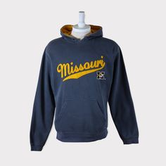 Embroidered Vintage 90s Missouri Tigers (University of Missouri) Football/Baseball/Basketball/Hockey NCAA Hoodie 💯 SATISFACTION AND AUTHENTICITY ⭐ MEASUREMENTS (when laid flat) Size on Tag: M Length: 69cm or 27 inches Armpit to armpit: 57cm or 22.5 inches ⭐ CONDITION 9/10 (Very good) Details: No holes Material: Cotton Color: Gray Brand: J America 🔷 Please give us your phone no. together with address after you purchased. 🔷Please keep in mind that our items are vintage so they may show some sig Vintage Hoodie With Double-lined Hood For Sports, Casual Sports Season Hoodie For Fans, Varsity Long Sleeve Hoodie For Fan Merchandise, Varsity Hoodie For Fan Merchandise, Varsity Cotton Long Sleeve Hooded Jacket, Casual Hoodie With Embroidered Graphics For College, Throwback Fan Merchandise Hoodie Sweatshirt, Varsity Cotton Hooded Jacket With Long Sleeves, Casual Sweatshirt With Embroidered Logo For Fans