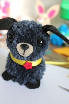 a blue stuffed animal with a yellow collar and red bow tie sitting on a table