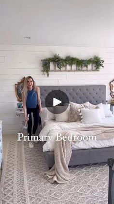 a woman standing next to a bed in a bedroom