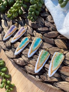 five pieces of jewelry sitting on top of a wooden table next to some green plants