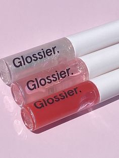 three lip glosses with the words glossier, glossier and glosser written on them