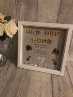 a photo frame with the words our new home spelled in scrabble and flowers