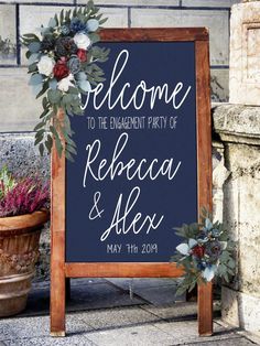 a welcome sign with flowers and greenery on it