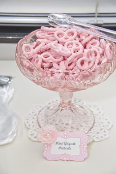 a glass bowl filled with pink pretzels sitting on top of a white table