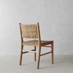 a wooden chair with wicker seat and backrest, against a white wall background