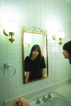 a woman standing in front of a bathroom mirror